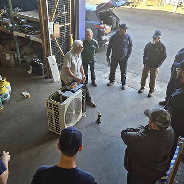 Air Conditioning Repairs 1_600x600 Team of technicians standing around Mini-Split unit in team meeting.