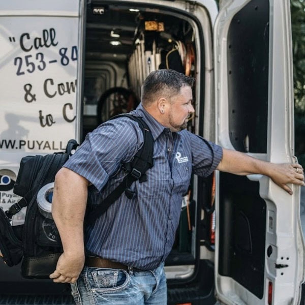 Puyallup HVAC technician closing door of branded van outside of residential property.