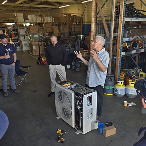 Team of technicians having a team meeting next to mini-split.
