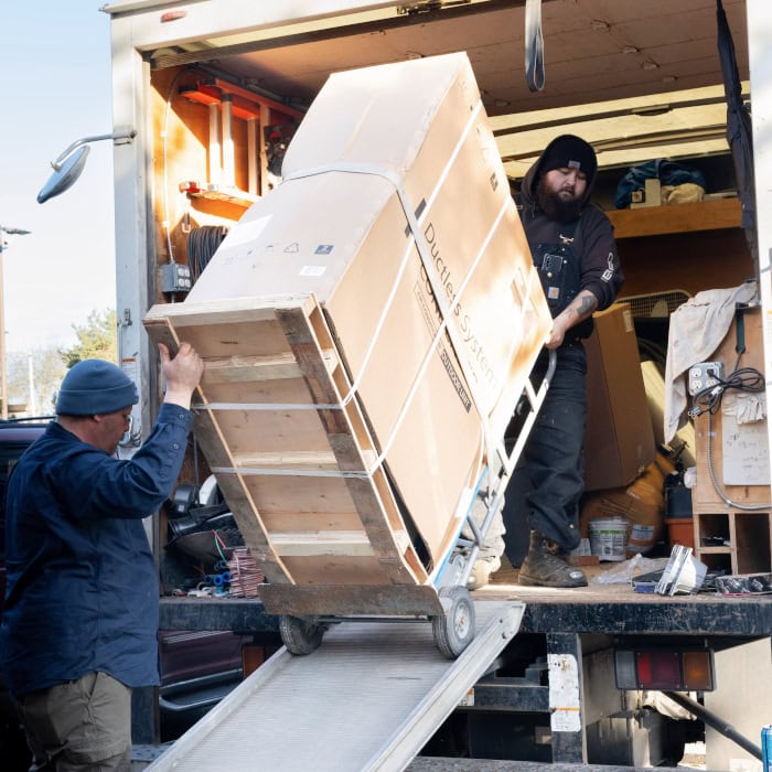 Puyallup HVAC technicians removing equipment from company branded truck.