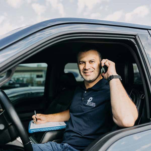 Puyallup Heating & Air Conditioning technician sitting in branded work truck in a parking lot.