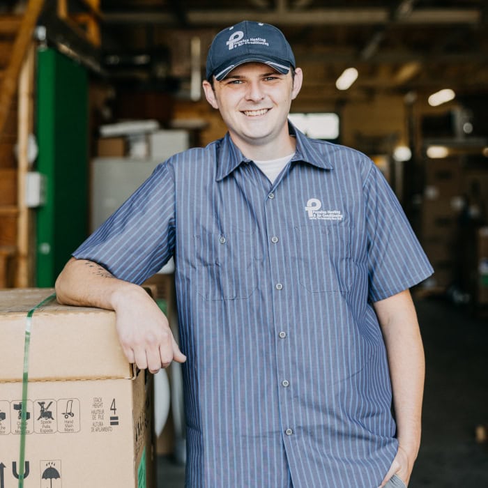 Puyallup HVAC technician standing in warehouse against equipment.