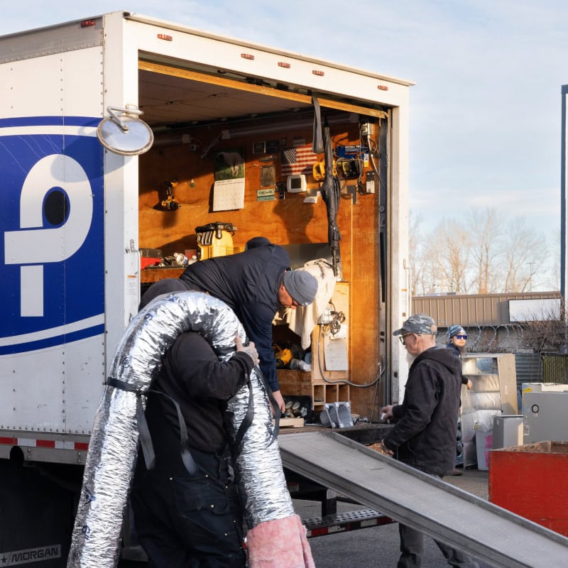 Puyallup HVAC technicians removing equipment from branded work truck.