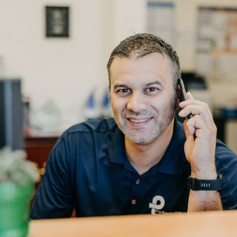 Puyallup HVAC technician answering phone in warehouse.