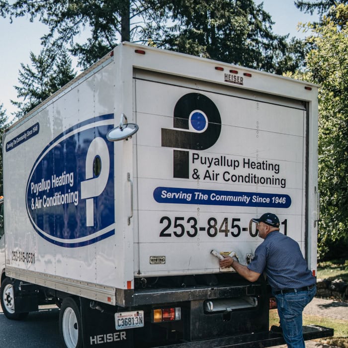 Puyallup HVAC technician closing back door on company branded work truck.
