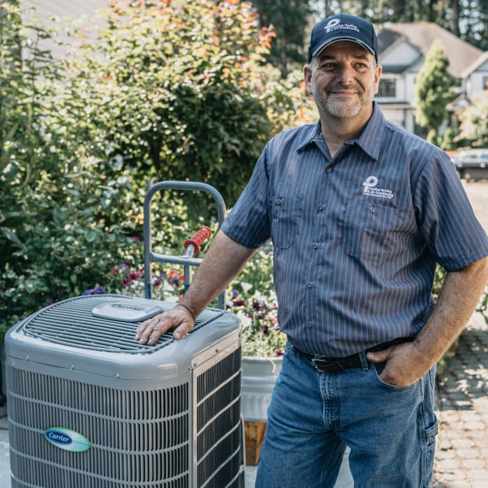 Puyallup HVAC technician standing with new heat pump.