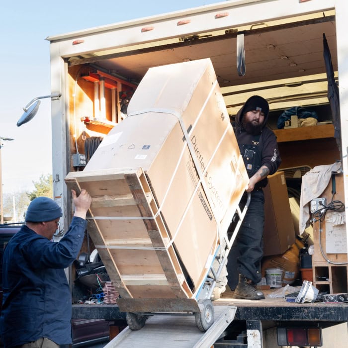 Puyallup HVAC technicians removing equipment from company branded truck.